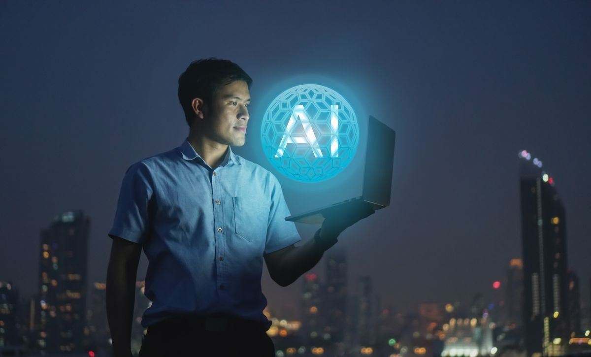 Businessman stand on roof top using laptop with hold the (AI)Artificial intelligence hologram,smart city and network connect concept
